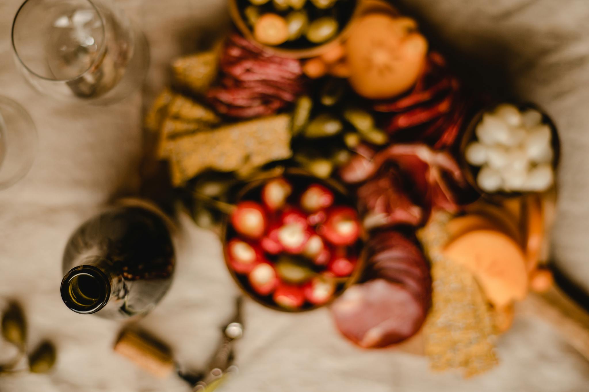 A vibrant charcuterie board filled with meats, cheeses, and olives paired with a bottle of red wine.