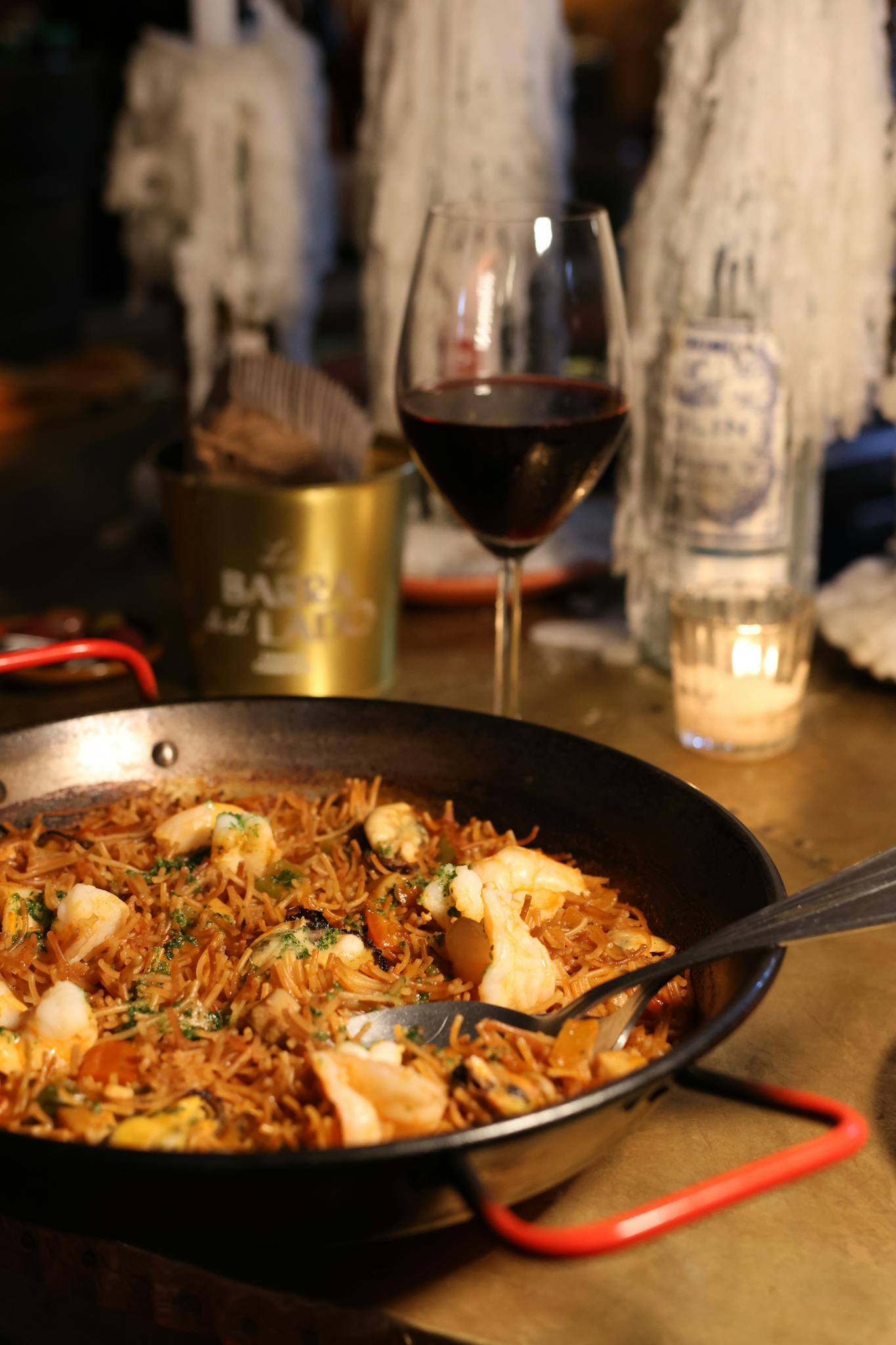 Indulge in traditional fideuà with seafood and wine in a cozy rustic setting, perfect for food lovers.