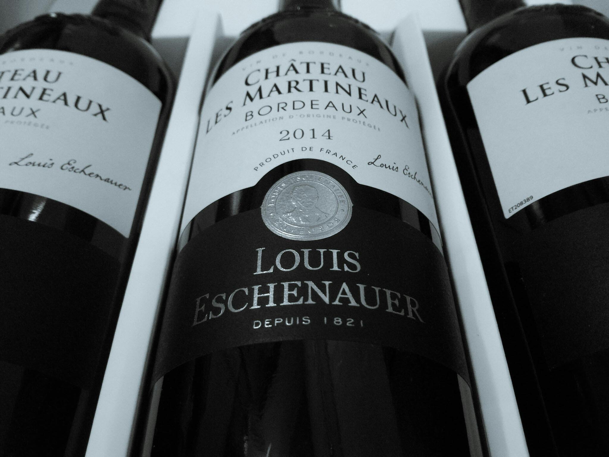 Three Louis Eschenauer wine bottles showcasing elegant labels in a monochrome setting.